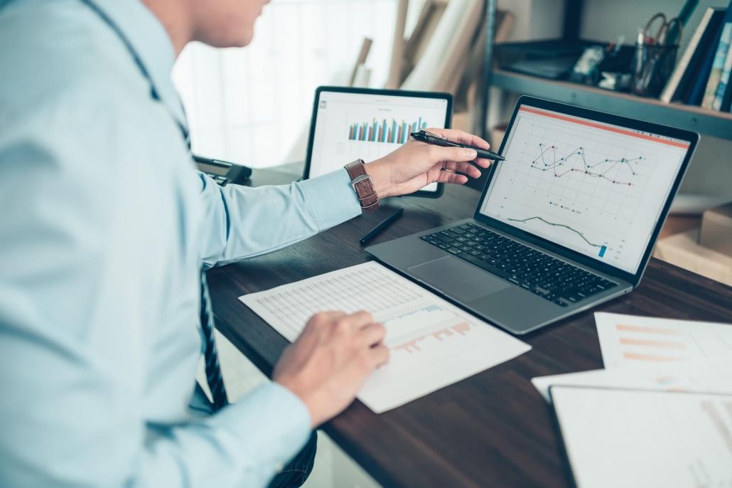 Man examining charts and graphs on his laptop at his desk.