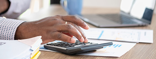 Man punching in calculations on calculator at desk