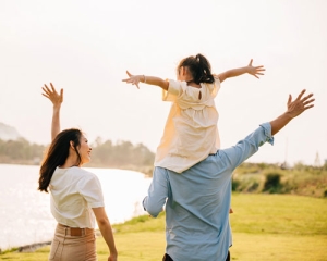Happy Asian family by a body of water in a park.
